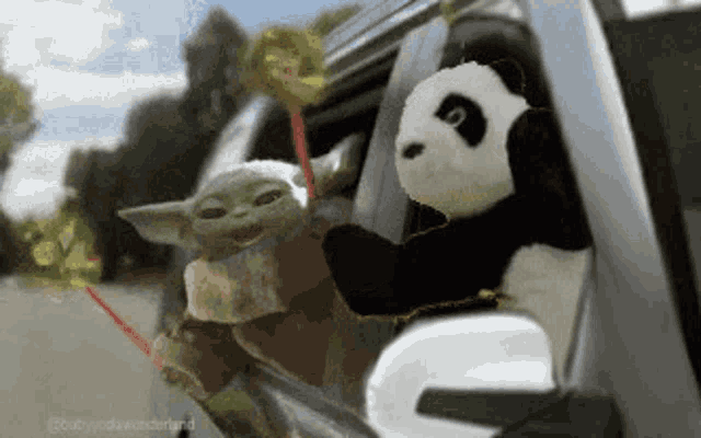 a baby yoda and a panda are looking out of a car window