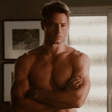 a shirtless man is standing with his arms crossed in a room .