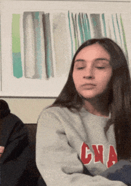 a girl wearing a grey sweater with cna written on it