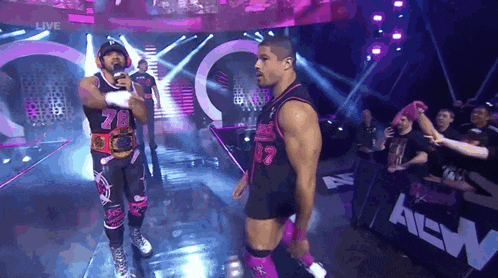 two wrestlers are standing on a stage in front of a crowd and one has the number 78 on his shirt