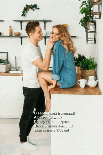 a man is touching a woman 's face while she sits on a kitchen counter