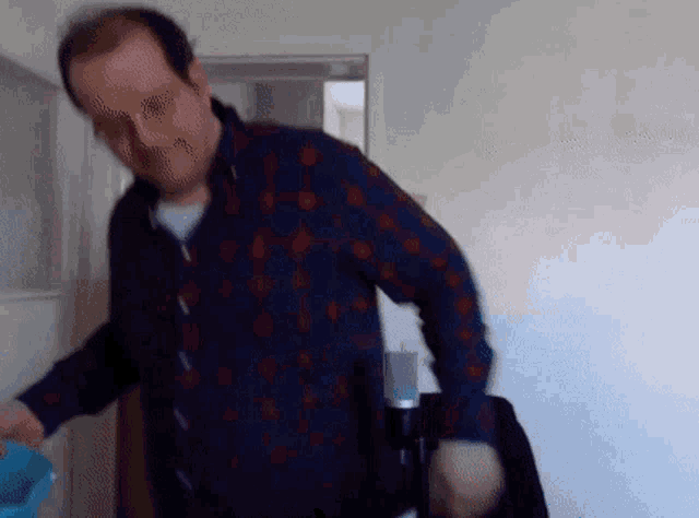 a man in a blue and red plaid shirt is standing in front of a door