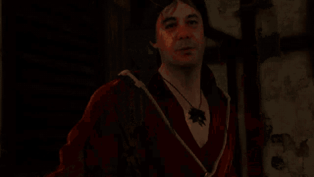 a man wearing a red shirt and a black necklace