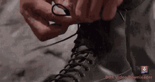 a close up of a person tying their boots with a box video downloader logo in the background