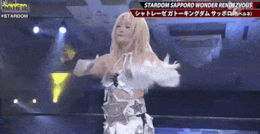 a woman is standing on a stage in a wrestling ring wearing a white top and gloves .