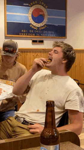 a man is eating a sandwich in front of a sign that says freedom is not free