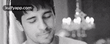 a black and white photo of a man with his eyes closed in front of a window .