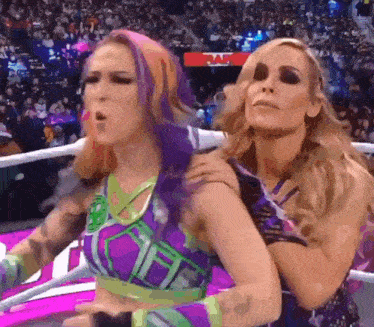 two women are wrestling in a ring with a crowd watching .