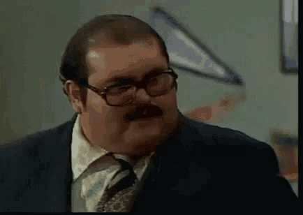 a man with glasses and a mustache is wearing a suit and tie