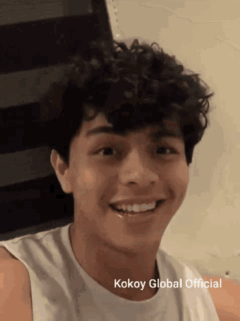 a young man with curly hair is smiling with the words kokoy global official above him