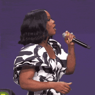 a woman singing into a microphone with a purple background