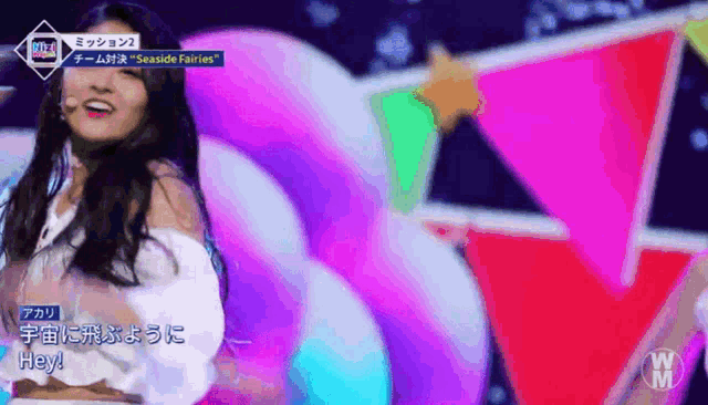 a woman stands on a stage in front of a giant unicorn float and says hey