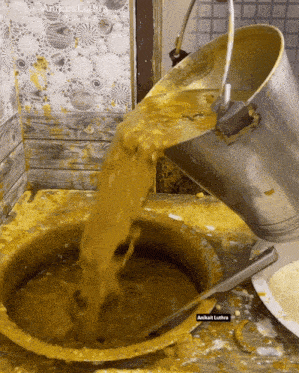 a bucket of yellow liquid is being poured into a bowl with a label that says anitkat lutra