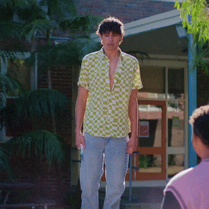 a man in a green and white checkered shirt is standing outside of a building