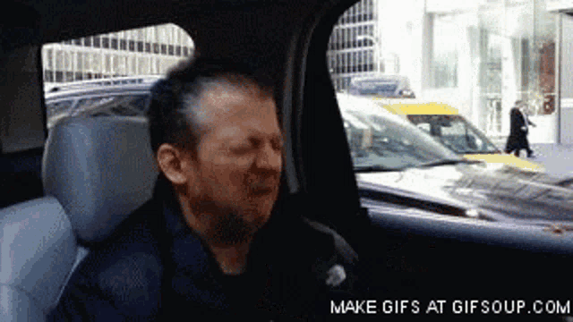 a man is sitting in the back seat of a car looking out the window ..