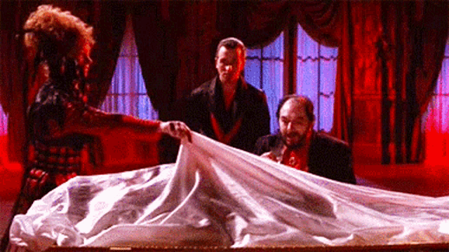 a woman is standing next to a coffin with a white cloth on it .