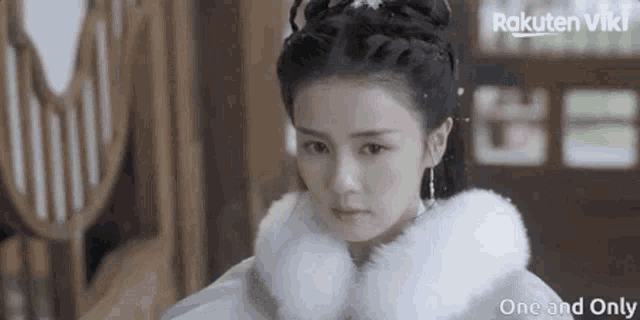 a woman in a white fur coat is looking at the camera