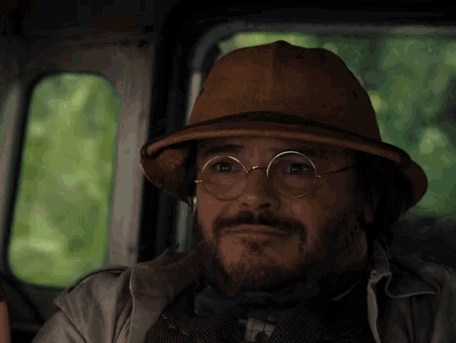 a man wearing a hat and glasses is sitting in a car