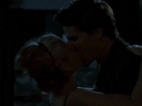 a man and a woman are kissing in a room