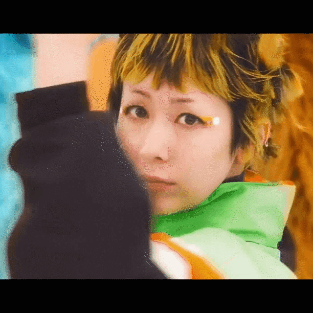 a close up of a woman 's face with yellow hair and a black glove