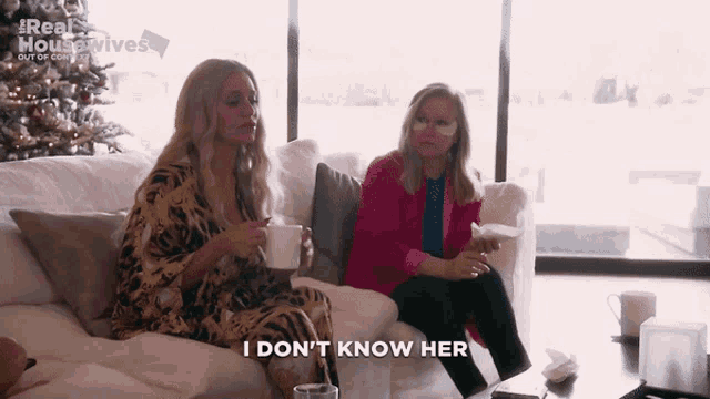 two women are sitting on a couch and one of them is saying i don t know her