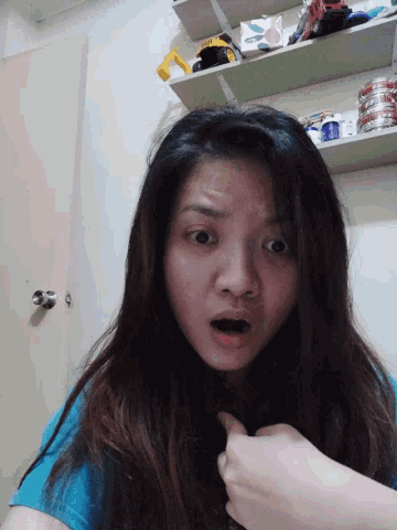 a woman in a blue shirt is making a funny face with her mouth open