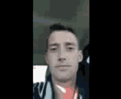 a man is sitting in the back seat of a car and taking a selfie .