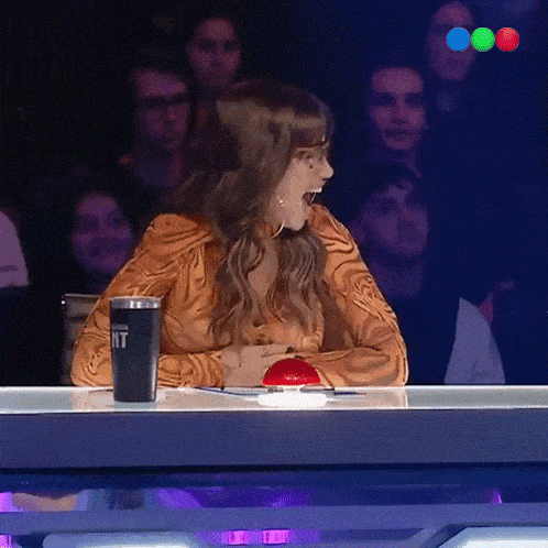 a woman is sitting at a table with a red button and a cup that says nt on it