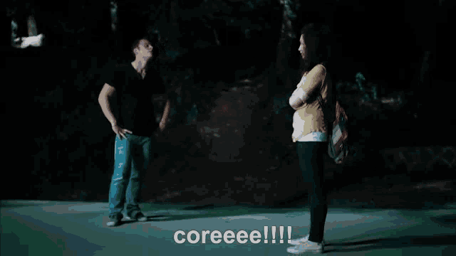 a man and a woman are walking down a road at night and the words coreeee !!! are visible