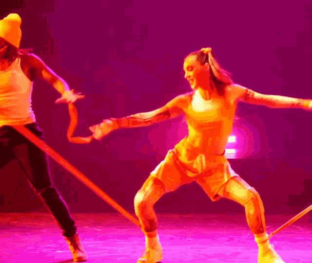 a woman in a yellow tank top and shorts is dancing on a stage