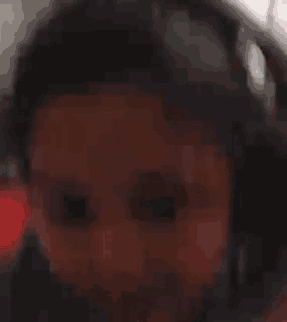 a blurry picture of a person wearing headphones and looking at the camera .