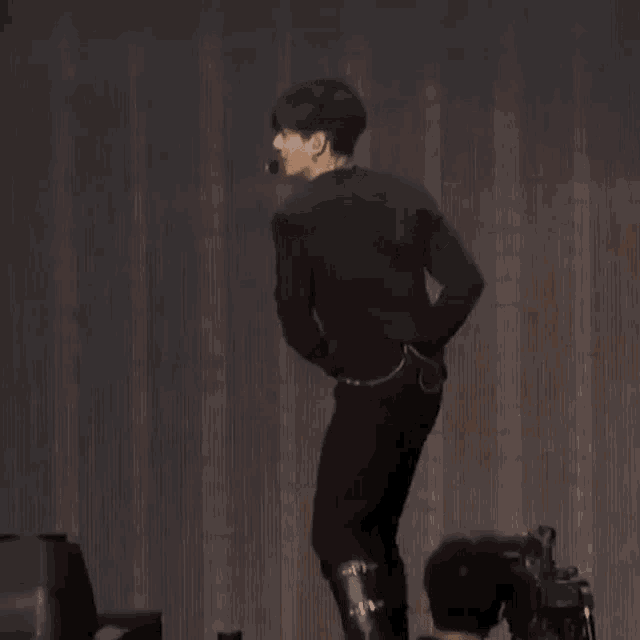 a man is standing on a stage with his hands on his hips .