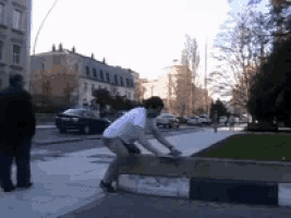 a man in a white shirt is doing a trick on a skateboard on a sidewalk