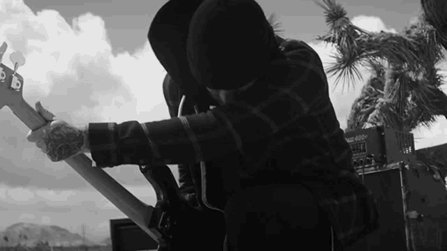 a black and white photo of a man playing a guitar in front of an orange amplifier