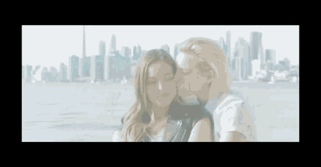 a woman is kissing another woman on the cheek while standing in front of a city skyline .