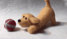 a stuffed animal dog is playing with a red ball