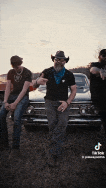 a man in a cowboy hat is standing next to two other men