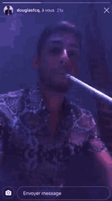a man in a snake print shirt is smoking a hookah in a dark room .