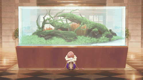 a woman sits in front of a large aquarium
