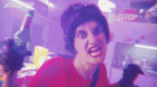 a woman in a red shirt is making a funny face in a purple room .