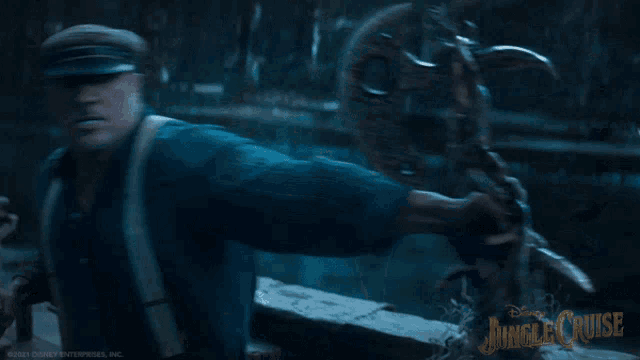 a man in a blue shirt is holding a statue with jungle cruise written on the bottom right