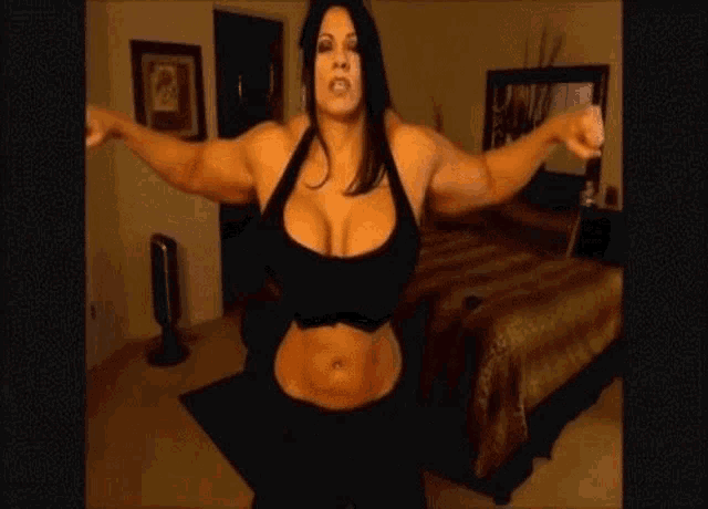 a very muscular woman is standing in a room with her arms outstretched .