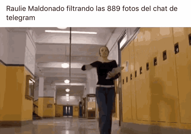 a woman is walking down a hallway with yellow lockers in a school