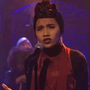 a woman is singing into a microphone with the words no more written on it .