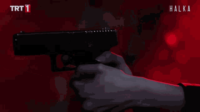 a person holding a gun in front of a red background that says trt 1 on it