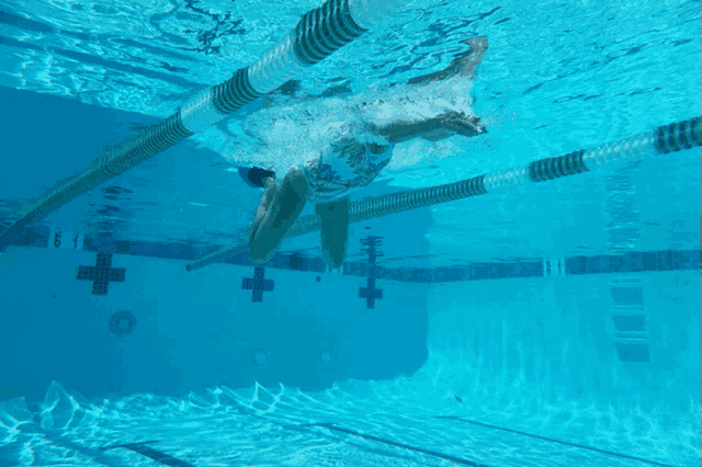 a person is swimming in a pool with a white cross on the side