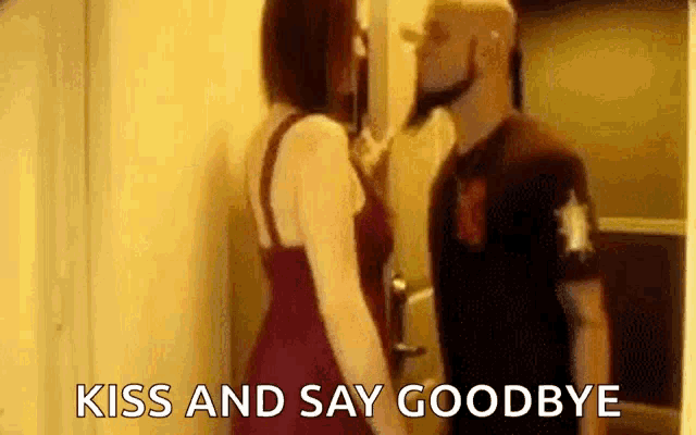 a man and a woman are kissing and saying goodbye in a room .