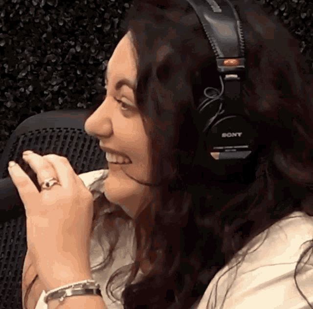 a woman wearing a pair of sony headphones smiles