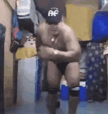 a shirtless man wearing a hat and underwear is standing in a closet .