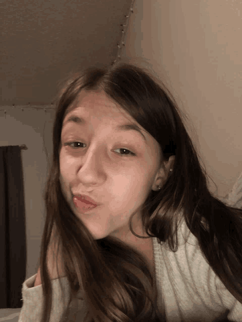 a girl with long brown hair is making a face